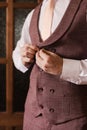 the groom buttons up his vest. Groom's wedding preparations