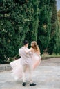 Groom carries bride in his arms along the path in the olive grove on Lake Como, Italy. Back view