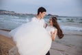 Groom carries bride in his arms on ocean beach. Just married happy couple have fun at wedding day Royalty Free Stock Photo