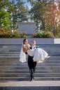 Groom carries his bride in his arms on the stairs Royalty Free Stock Photo