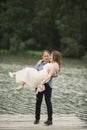 Groom carrying bride near lake and forest Royalty Free Stock Photo