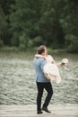 Groom carrying bride near lake and forest Royalty Free Stock Photo