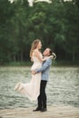 Groom carrying bride near lake and forest Royalty Free Stock Photo