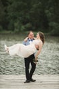 Groom carrying bride near lake and forest Royalty Free Stock Photo