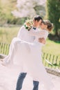 Groom carrying his beautiful bride on arms leaning foreheads at spring park Royalty Free Stock Photo