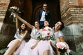 Groom with the charming bridesmaids with the bouquets Royalty Free Stock Photo