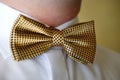 Groom with closeup fashioned golden bowtie and white shirt