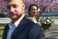Groom in defocus blues in the foreground, in the background in focus is weightless with flowers. bride, against the background of Royalty Free Stock Photo