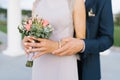 The groom embraces the bride, a large view of the hands. The bride holds a delicate bouquet of flowers Royalty Free Stock Photo