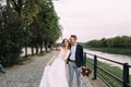 The groom embraces the bride on the river bank. Stylish young and beautiful couple Royalty Free Stock Photo