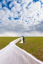 The groom embraces the bride, which has long veil flies through the air Royalty Free Stock Photo