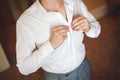 The groom fastens a button on a white wedding shirt. Royalty Free Stock Photo