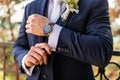 Groom fixing his cufflinks. Handsome groom dressed in dark blue formal suit getting ready for wedding. Elegant groom.