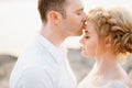The groom gently kisses the bride on the forehead on the rocks by the sea, close-up Royalty Free Stock Photo