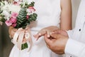 The groom gently puts on a wedding gold ring on a fragile female hand at a marriage ceremony