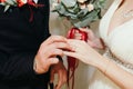 The groom gently puts on a wedding gold ring on a fragile female hand at a marriage ceremony