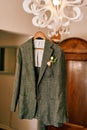 Groom gray jacket hangs on a chandelier in a hotel room