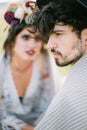 Groom in a hat and plaid sits next to bride in a wreath