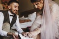 Groom helps charming bride in pink dress to put on keds