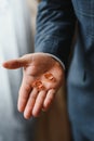 The groom on his wedding day holds two wedding rings in his hand in a hotel room. The man is wearing a white shirt and Royalty Free Stock Photo