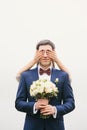 Groom holding bouquet bride closes his eyes with hands Royalty Free Stock Photo