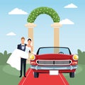Groom holding bride in his arms and red classic car in just married scenery