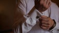 Groom is holding hands on the tie, wedding suit. close up of a hand man how wears white shirt and cufflink. Business man