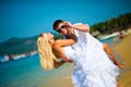 Groom holding his bride on the beach against the sea and adjusts his sunglasses Royalty Free Stock Photo