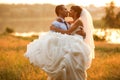 Groom is holding and kissing his bride on the background evenin Royalty Free Stock Photo