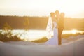 Groom is holding and kissing his bride on the background sunset Royalty Free Stock Photo