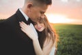 Groom is holding and kissing his bride on the background sunset Royalty Free Stock Photo