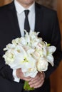 The groom holding a wedding bouquet of flowers in his hands, waiting for his bride. bridal bouquet of white lilies and Royalty Free Stock Photo