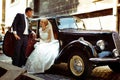 Groom holds an arm of a charming bride while she sits in an open