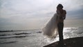 Groom holds bride in his arms on background of sea. Action. Groom picked up bride and turns her in sun on background of Royalty Free Stock Photo