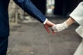 Groom holds bride`s arm in a white glove walking around the city Royalty Free Stock Photo
