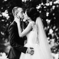 Groom holds bride tender while she kisses him in the garden