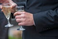 The groom holds a glass or flute of champagne on the background of the friends on nature at the wedding ceremony. Close Royalty Free Stock Photo