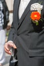 The groom holds a glass or flute of champagne on the background of the friends on nature at the wedding ceremony. Close Royalty Free Stock Photo