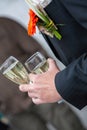 The groom holds a glass or flute of champagne on the background of the friends on nature at the wedding ceremony. Close Royalty Free Stock Photo