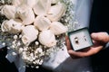 The groom holds in his hands a decorative box with wedding rings and a beautiful wedding bouquet Royalty Free Stock Photo