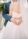 Groom holds his hands in the shape of a heart on the back of the bride in a white dress, hugging her Royalty Free Stock Photo