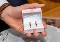 Groom holds a jewelry gift box with gold wedding rings