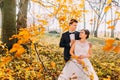 The groom is hugging the bride back behind the sticks with yellowed leaves. Royalty Free Stock Photo