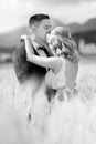 Groom hugging bride tenderly and kisses her on forehead in wheat field somewhere in Slovenian countryside. Royalty Free Stock Photo