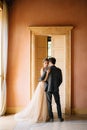 Groom hugs bride against the background of the high door to the room of the old villa. Lake Como. Close up Royalty Free Stock Photo