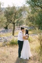 Groom hugs bride in the garden of olive trees