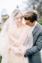 Groom hugs bride in a veil from behind and kisses her on the shoulder, in the garden. Lake Como, Italy. Close up Royalty Free Stock Photo
