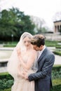 Groom hugs bride in a veil from behind and kisses her shoulder Royalty Free Stock Photo