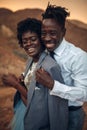 Groom hugs his bride dressed in his jacket in canyon at sunset a