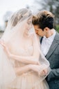 Groom hugs smiling bride in a veil from behind and kisses her on the shoulder. Lake Como, Italy Royalty Free Stock Photo